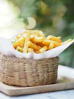 pommes frites, kartoffelchips gelbe knusprige pommes im holzkorb auf weißem tisch, leckerer snack foto