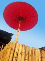 Der rote Regenschirm befindet sich auf einem Bambusstamm. foto