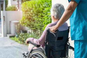 Pflegekraft hilft und pflegt asiatische Senioren oder ältere Frauen, die im Rollstuhl auf der Rampe im Pflegekrankenhaus sitzen, gesundes, starkes medizinisches Konzept foto