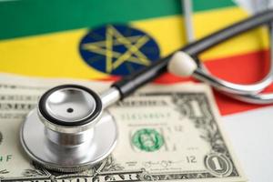 Schwarzes Stethoskop auf Äthiopien-Flaggenhintergrund mit US-Dollar-Banknoten, Geschäfts- und Finanzkonzept. foto