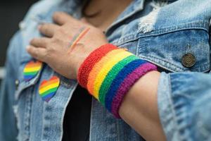 asiatische dame mit regenbogenflaggenarmbändern, symbol des lgbt-stolzmonats, feiert jährlich im juni die sozialarbeit von schwulen, lesbischen, bisexuellen, transgendern und menschenrechten. foto