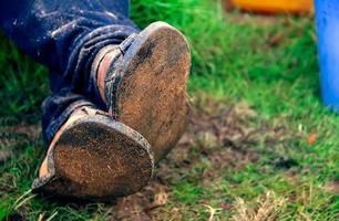 Füße einer Person gekreuzt und auf einem grünen Gras ruhend. gekreuzte Beine auf dem Boden foto