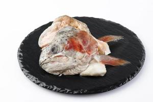 Gefrorener Lachsfischkopf auf schwarzer Schieferplatte foto