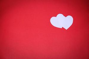 weißes herzförmiges papier auf rotem hintergrund mit dem konzept valentinstag foto