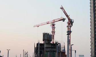 abstrakter industrieller Hintergrund mit Baukränen Silhouetten über erstaunlichen Sonnenuntergang Himmel foto