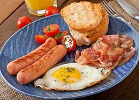 Englisches Frühstück - Toast, Ei, Speck und Gemüse im rustikalen Stil auf Holzhintergrund foto
