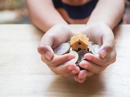 Haus- oder Hausmodell und Münzen auf der Hand mit Hausschlüssel. konzept für darlehen, immobilienleiter, finanzen, hypotheken, immobilieninvestitionen, steuern und bonus. foto