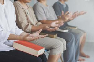 asiatische christliche gruppen, die in der katholischen kirche saßen, beteten um segnungen von gott. eine fahle Sonne schien auf einen Ort der Anbetung.religiöse Konzepte. foto