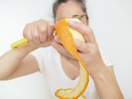 neunundvierzig Jahre alte Frau in einem weißen T-Shirt vor einem weißen Hintergrund mit einer Orange foto