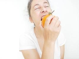 neunundvierzig Jahre alte Frau in einem weißen T-Shirt vor einem weißen Hintergrund mit einer Orange foto