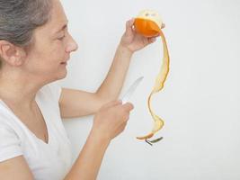 neunundvierzig Jahre alte Frau in einem weißen T-Shirt vor einem weißen Hintergrund mit einer Orange foto