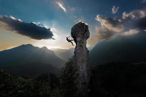 Doppelseil-Abseilen eines Kletterers von einer Felsspitze in einer märchenhaften Landschaft foto