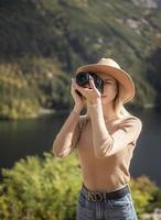 fotograf tourist reisender steht auf grüner spitze auf berg und hält in den händen digitalfotokamera foto