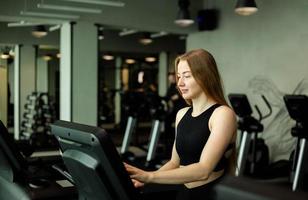 glückliche sportliche Frau, die auf Laufbändern in einem Fitnessstudio joggt. foto