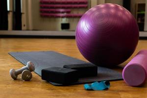 Satz Sportgeräte mit Fitnessball und Yogamatte im Fitnessstudio auf dem Boden foto