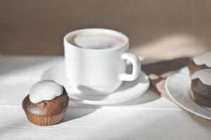 Tasse Milchkaffee und frisch gebackene Cupcakes mit Zuckerguss. Morgens selbstgebackene Schoko-Muffins. natürliches Licht. foto