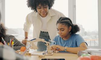 Klassenzimmer mit verschiedenen Lernenden von fröhlichen afroamerikanischen Schülern und Lehrern, die gemeinsam Aktivitäten unternehmen. Der Lehrer unterrichtet, leitet und spricht mit den Kindern in verschiedenen Bereichen. foto