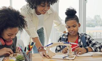 Klassenzimmer mit verschiedenen Lernenden von fröhlichen afroamerikanischen Schülern und Lehrern, die gemeinsam Aktivitäten unternehmen. Der Lehrer unterrichtet, leitet und spricht mit den Kindern in verschiedenen Bereichen. foto