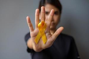 Suizidpräventionstag, Sarkom-, Knochen-, Blasen- und Kinderkrebsbewusstseinsmonat, gelbes Band zur Unterstützung von Menschen, die leben und krank sind. konzept für kindergesundheit und weltkrebstag foto