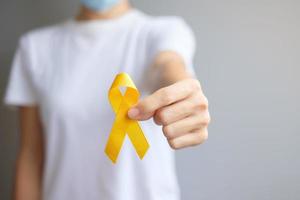 Suizidpräventionstag, Sarkom-, Knochen-, Blasen- und Kinderkrebsbewusstseinsmonat, gelbes Band zur Unterstützung von Menschen, die leben und krank sind. konzept für kindergesundheit und weltkrebstag foto