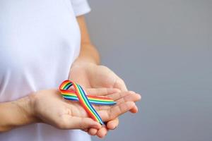 Hand, die ein lgbtq-Regenbogenband hält, um das Konzept der Lesben-, Schwulen-, Bisexuellen-, Transgender- und Queer-Gemeinschaft und des Stolzmonats zu unterstützen foto