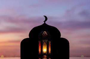 Laterne mit verschwommenem Fokus auf Moscheenhintergrund mit Mondsymbol oben und Morgenhimmel. foto