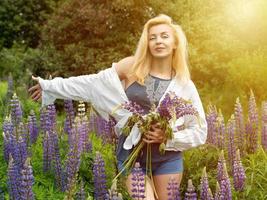 Frau geht im Garten voller Lupinen spazieren foto