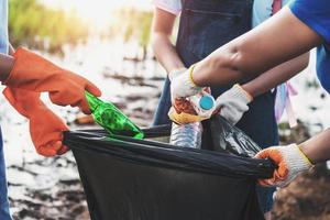 freiwillige frau, die müllplastik zur reinigung im river park aufsammelt foto