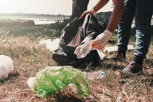 freiwillige frau, die müllplastik zur reinigung im river park aufsammelt foto