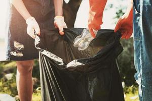 freiwillige frau, die müllplastik zur reinigung im river park aufsammelt foto