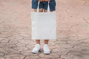 junges modell, das weiße einkaufstasche für leere schablone des modells hält foto