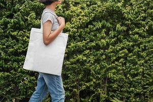 Hipster-Frau mit weißer Baumwolltasche im Park foto