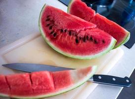 Wassermelonenscheiben auf Schneidebrett mit Messer