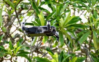 niemand, moderne schwarze Drohne, die in der Natur mit 4 Propellern, 4k-Kamerafoto und Video fliegt. das konzept für profis in der industrie der unbemannten flugzeugtechnik. Nahaufnahme, Zuschneiden, Hintergrund verwischen. foto