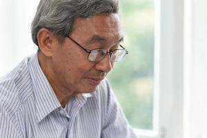 nahaufnahme älteres glückliches gesicht friedlicher ruhiger kluger blick mit brille asiatischer alter mann. foto