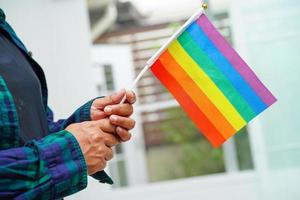 asiatische frau mit regenbogenflagge, lgbt-symbolrechten und geschlechtergleichstellung, lgbt-stolzmonat im juni. foto