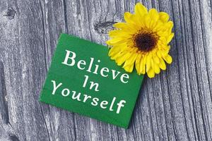 glaube an dich selbst wort auf grünem holzwürfel mit und sonnenblume. foto