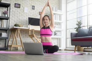 fitte junge frau, die zu hause yoga über online-unterricht mit professionellem ausbilder, sport und gesundem lebensstilkonzept praktiziert. foto