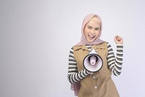 Glückliche muslimische Frau kündigt mit Megaphon auf weißem Hintergrund an foto