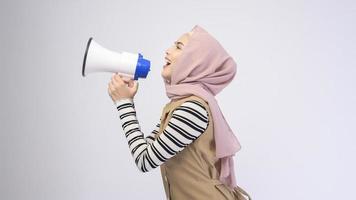 Glückliche muslimische Frau kündigt mit Megaphon auf weißem Hintergrund an foto