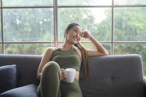 junge fitnessfrau in sportbekleidung, die nach dem training zu hause, gesund und lebensstil eine tasse kaffee trinkt. foto