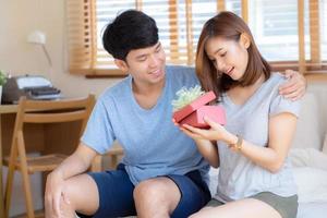 schönes junges asiatisches paar in der liebe überraschungsgeschenkbox im schlafzimmer zu hause, familienjubiläum mit genießen und romantisch zusammen ehefrau und ehemann mit beziehung, feiern valentinstag konzept. foto