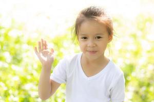 porträtgesicht des niedlichen asiatischen kleinen mädchens und des kindes glück und spaß im park im sommer, lächeln und glücklich vom asiatischen kind und entspannen im garten, lebensstil-kindheitskonzept. foto