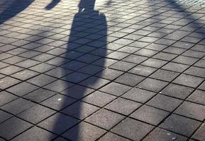 Schatten von Menschen in einem europäischen Einkaufsviertel auf einem Kopfsteinpflaster foto