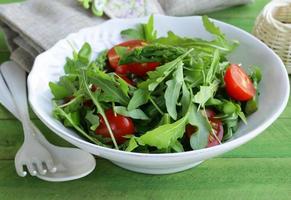 Salat mit Rucola und Tomaten auf einem Holztisch serviert