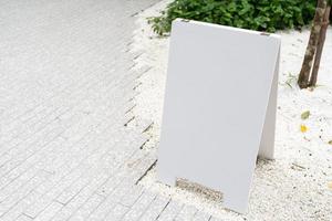 Weißes Mock-up-Holzschild auf Betonboden. leeres weißes schild draußen tagsüber. foto