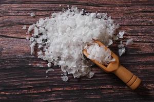 Blume des Salzes, ist ein Salz, das sich als dünne, zarte Kruste auf der Oberfläche des Meerwassers in der Holzschaufel auf Holzgrund bildet. foto