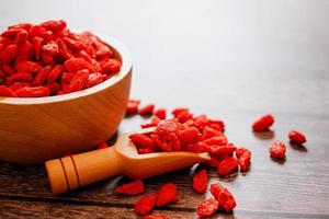 getrocknete chinesische Wolfsbeeren oder chinesisches Kraut der Goji-Beere oder Eherebe in der hölzernen Schaufel auf Holzschale isoliert auf Holzhintergrund. ausgewählten Fokus. foto