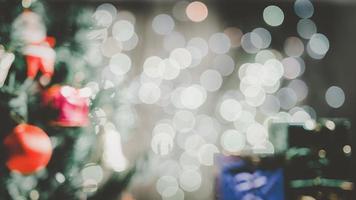 Hintergrundunschärfe von Weihnachtsbäumen mit Ornamenten, Geschenkboxen und Grünton-Bokeh. foto