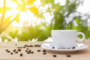 eine weiße kaffeetasse mit untertasse wird auf eine holzplatte und auf einen holzhintergrund gestellt. foto